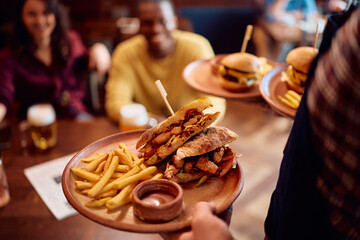 Close up of waiter serving food in pub.