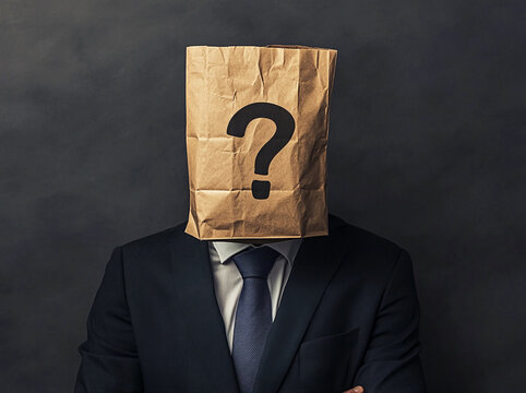 Mysterious person in business suit with paper bag over head standing against dark background