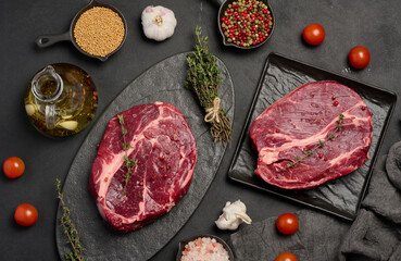 Raw beef steak chuck eye roll on wooden board. Spices for cooking Himalayan salt, peppercorns and...