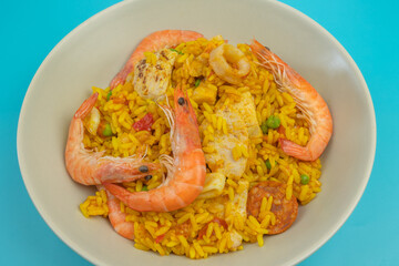 assiette de paella, vue du dessus, en gros plan,, isolée sur un fond bleu