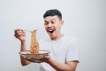 Excited Young Man Enthusiastically Enjoying a Bowl of Noodles in a Bright Setting