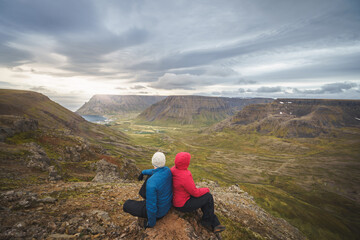 Fototapeta premium A married hiking couple on Bolafjall mountain overlooking Bolungarvik in Iceland’s Westfjords region.