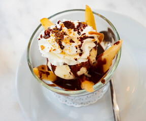Contrasting French dessert Poire belle Helene of hot poached pears with cold ice cream, whipped cream and chocolate syrup