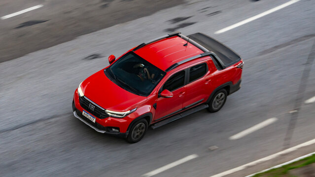 Red pickup truck cruising city highway, Fiat Strada in movement