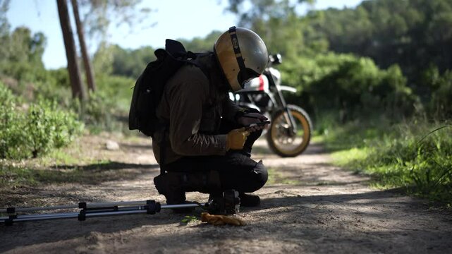 Toma en 4k de chico influencer colocando la camar apar agrabarse con su moto en un camino de tierra entre arboles
