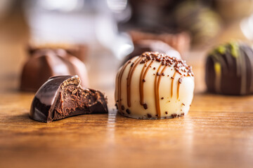 Bitten chocolate praline on wooden table.