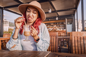 Tourist making a disgusted face while drinking a bad coffee in an outdoor cafe