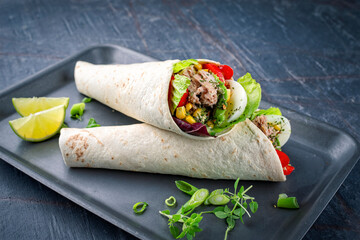 Italian style Wrap Piada wheat Tortilla with tuna fish, corn, vegetable salad and hard boiled egg seried on tray