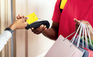 African American Woman Making Payment With Credit Card And Terminal Paying Courier Guy For Shopping...
