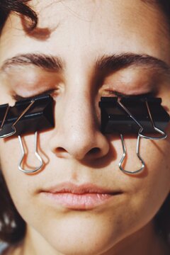 Closeup portrait of girl with paper clips on her eyes 