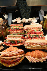 Mouth-watering meat and vegetable rolls, salmon and ham sandwiches; nuggets in the cafe window