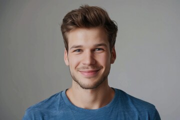 Fototapeta premium Close up portrait of smiling handsome guy in blue t shirt isolated on gray background