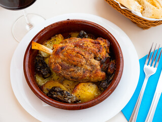 Shank baked in oven in a bowl with sliced potato and green peppers served in a plate