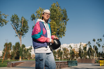 Young skater holding helmet in skate park, enjoying sunny day © Zamrznuti tonovi
