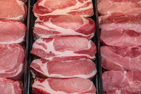 Various cuts of meat on display in grocery store refrigerator case.