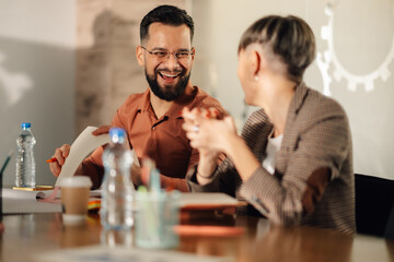 Colleagues laughing together during meeting at office table