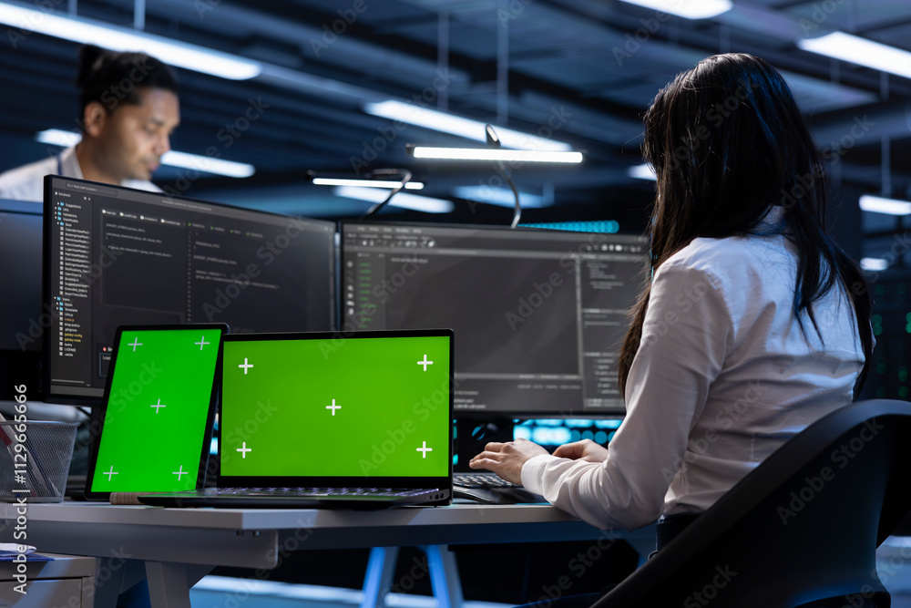Poster coworkers in data center using green screen laptop and tablet to find firewall misconfigurations aff