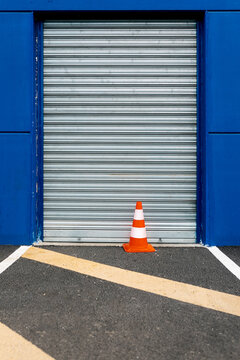 Orange Traffic Cone in Front of a Closed Blue Garage Door