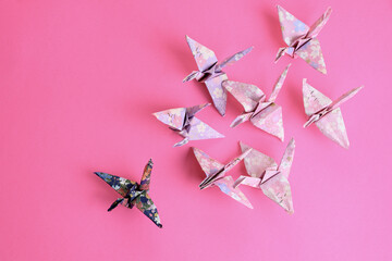 Pink and blue origami swans on a pink background