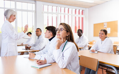 Doctors different age sitting at desk in classroom working during lesson at adult education class