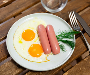 Appetizing fried eggs with sausage served on plate for breakfast
