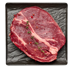 Raw piece of beef and sprig of thyme on black board, top view. Isolated background