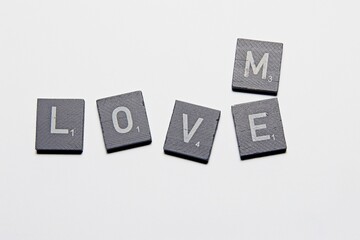 Gray Scrabble Letters making the word Love Me, on a White background