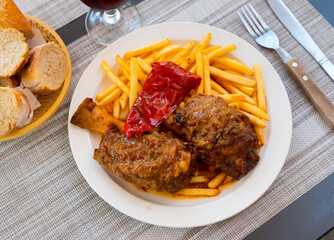 Pork knuckle with potatoes and stewed bell peppers closeup