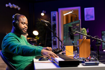 Audio designer enhancing sound quality on his audio files with mixing console and amplifier, editing in post production. Skilled music producer operating faders and pre amp knobs.