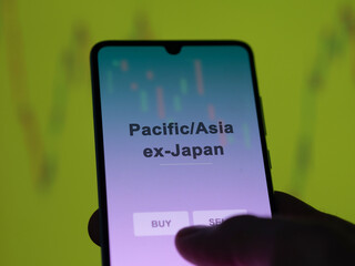 An investor analyzing the pacific/asia ex-japan etf fund on a screen. A phone shows the prices of...