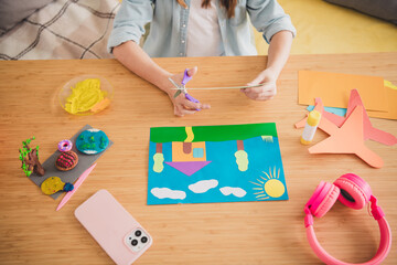 Young girl enjoying creative crafting at home with colored paper and clay on a sunny weekend day indoors
