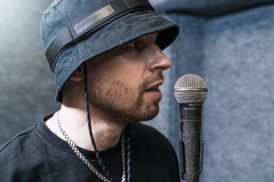 Hip-hop artist recording vocals in professional studio, performing into microphone, expressing rhythm and flow, modern music scene, creative energy and urban trend.