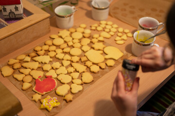 Little girl with glasses making Christmas cookies at home in the kitchen