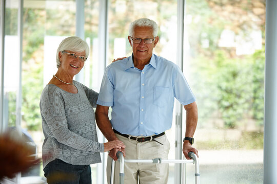 Walking, frame and portrait of senior couple in nursing home with support, recovery and help for balance. Retirement, health and mature person with disability for mobility, movement and wellness