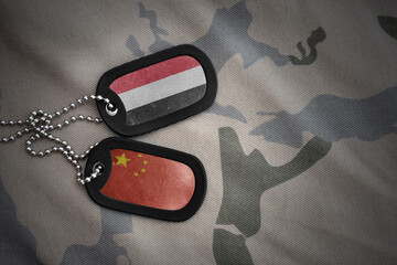 vintage army blank, dog tag with flag of yemen and china on the khaki texture background. military...