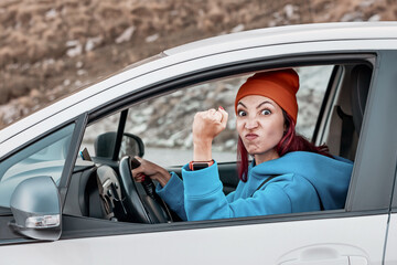 Angry female driver shaking fist at another car while driving