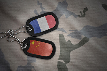 vintage army blank, dog tag with flag of france and china on the khaki texture background. military...