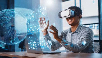 Exploring the Metaverse: Man wearing VR headset interacts with a digital globe, laptop nearby.  Innovative technology, futuristic concepts. 