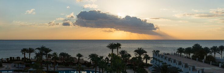 Sunrise on the sea coast. The movement of the sun and clouds across the sky. Park recreation areas of Egypt. Garden and landscape design.