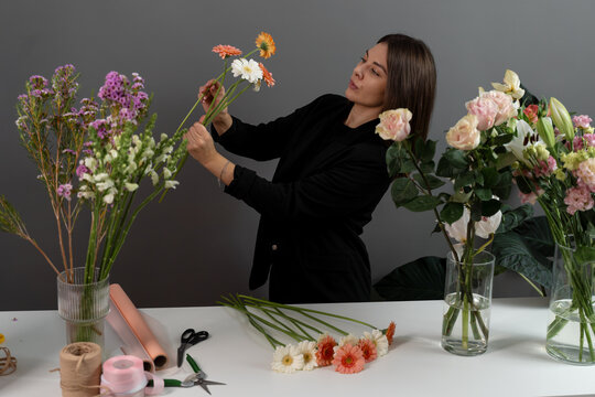 Florist is collecting daisy flowers for bouquet in floral shop. Making flower composition from gerberas for customers.