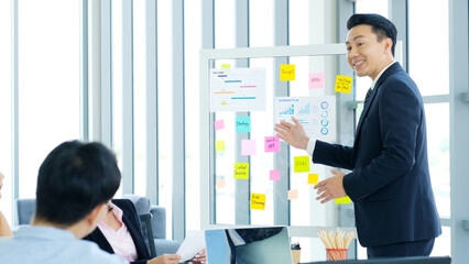 Businessman presenting business plan information to team at office meeting, Asian leader man explaning business chart for teamwork, business people, success in business concept
