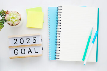 2025 on wood box, blank notebook paper on white marble table background, 2025 new year mock up, template with copy space for text, top view