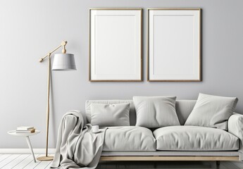 Two empty frames on a grey wall above a white sofa with a throw and pillows in a minimalist living room