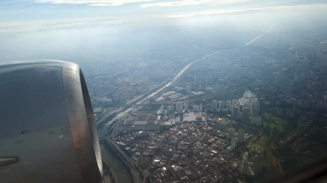 View through the airplane window during a flight over the city of Sao Paulo, passing over the Tiete River, Lapa region in the West Zone.