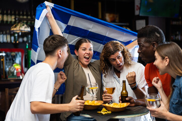 Enthusiastic Greek fans scream with joy in a beer bar. Greece win
