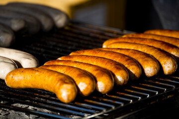On the grill, sausages of various colors are neatly arranged