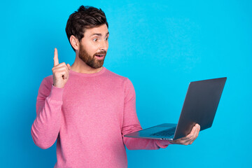 Excited young man with a new idea holding laptop on blue background