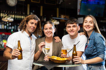 Portrait of happy friends in a beer bar chatting and drinking beer