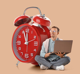 Young businessman in eyeglasses working with laptop on beige background