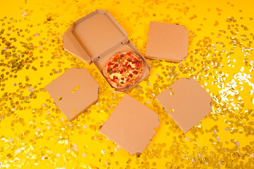 Tasty pizza with confetti on yellow background